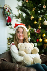 Obraz na płótnie Canvas Pretty young girl hugs teddy bear in christmas eve