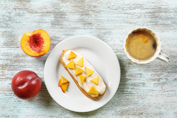 Delicious eclair and cup of coffee on wooden table