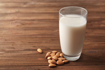 Glass of tasty almond milk on  wooden table