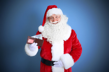 Santa Claus holding wallet with money and credit card on blue background