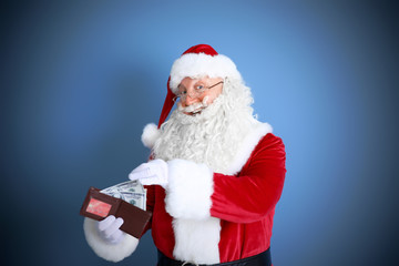 Santa Claus holding wallet with money and credit card on blue background