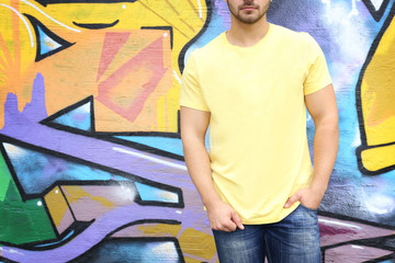 Young man in blank t-shirt against graffiti wall, closeup