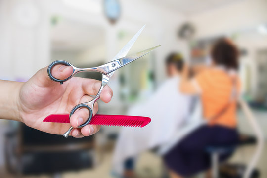 Hairdresser hold scissors with salon beauty background