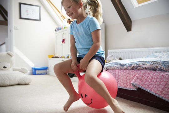 Girl Bounces On Inflatable Ball In Playroom