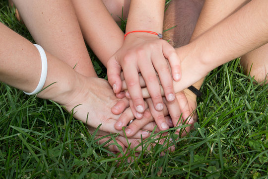 Hands top each other with grass background