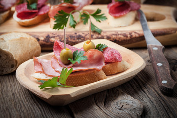 Tapas with sliced sausage, salami, olives and parsley.