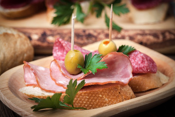 Tapas with sliced sausage, salami, olives and parsley.