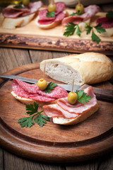 Tapas with sliced sausage, salami, olives and parsley.