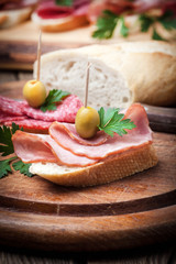 Tapas with sliced sausage, salami, olives and parsley.