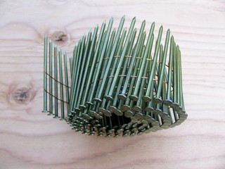 Coil nails in roll for nailer guns on plywood background