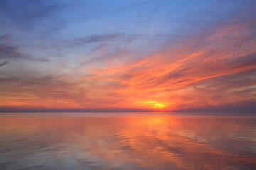 Fototapeta na wymiar Coastal Sunset, Red Clouds reflecting in Calm Sea