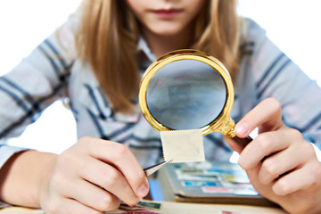 Teen girl with magnifier looks his stamp collection