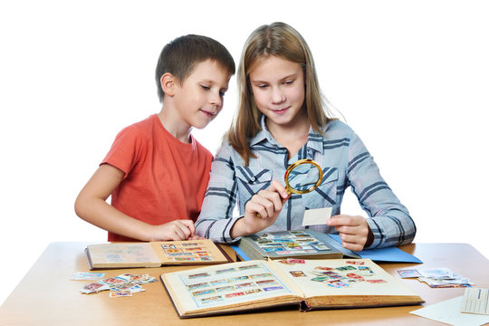 Teen girl and little boy with magnifier looking his stamp collection isolated