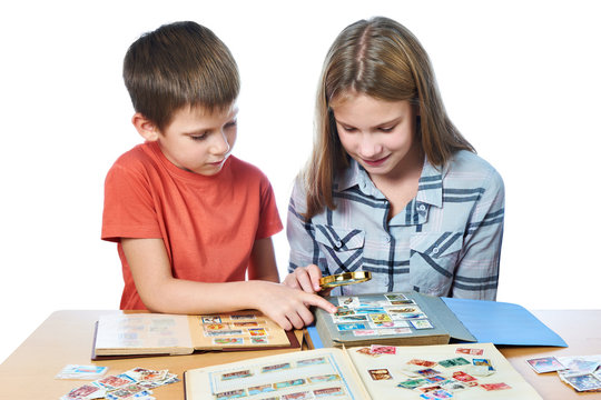 Teen girl and little boy with magnifier looking his stamp collec