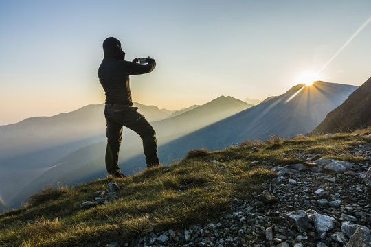 Hiker taking the picture the sunrise in the mountains.