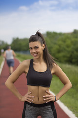 Fototapeta na wymiar Jogging girl in sportswear smile on tartan track