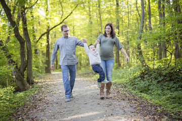 Fototapeta premium Happy pregnant family having fun in autumn nature