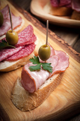 Tapas with sliced sausage, salami, olives and parsley.