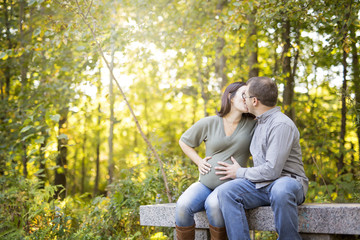 Fototapeta premium Beautiful pregnant couple relaxing outside in the park.