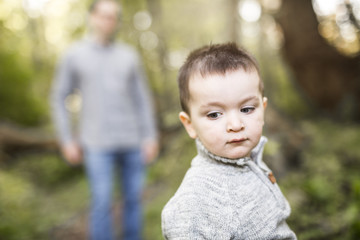 Little boy and his father on grass in autumn forest