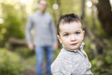 Little boy and his father on grass in autumn forest