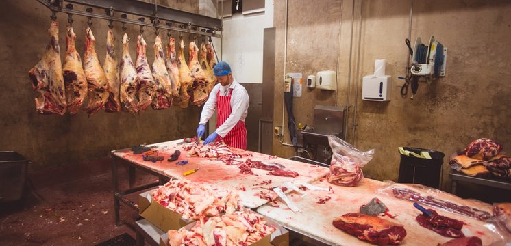 Butcher chopping meat in storage room