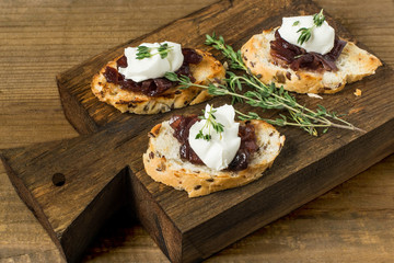 Fototapeta na wymiar Toasted slices of baguette with onion jam, cream cheese and thym