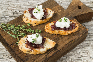 Toasted slices of baguette with onion jam, cream cheese and thym