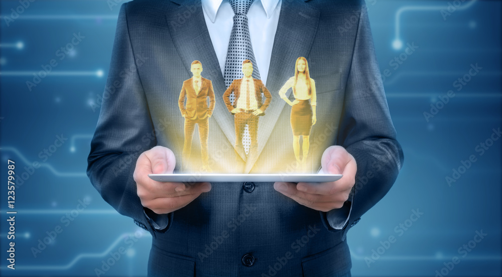 Wall mural Someone holding tablet that is showing hologram of two men and woman wearing office clothing - Wall murals