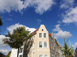 Schöner sanierter Giebel eines alten Eckhaus vor blauem Himmel mit weißen Wolken im Sonnenschein...