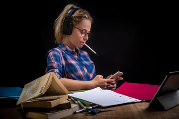 une adolescente écoute de la musique avec son smartphone au lieu de travailler