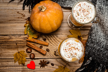 Pumpkin  spice latte with whipped cream on the rustic wooden background.