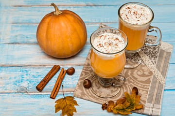 Pumpkin  spice latte with whipped cream on blue wooden background. Autumn background