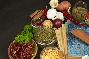 Cookbook and spices on wooden table. Cookbook and ingredients. Garlic, chili peppers and onion. Ingredients for cooking. Home Kitchen.
