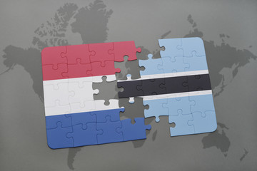 puzzle with the national flag of netherlands and botswana on a world map background.