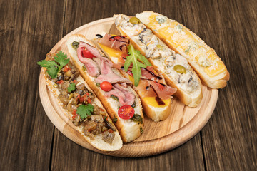 Snack consisting of five different sandwiches served on wooden plank on old wood table