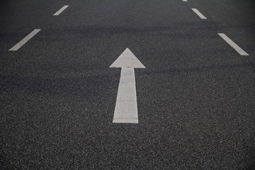 Geradeaus zeigender wei&szlig;er Pfeil auf grauer asphaltierter Strasse, vorw&auml;rts gerichtete pfeilf&ouml;rmige Stra&szlig;enmarkierung, perspektivische Ansicht