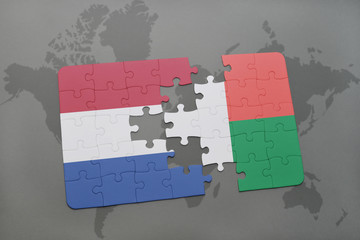 puzzle with the national flag of netherlands and madagascar on a world map background.