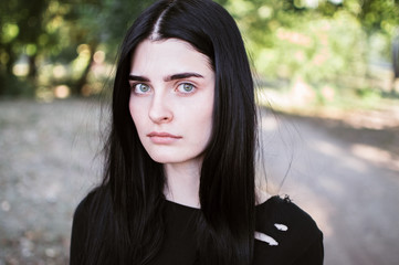 Outdoors portrait of beautiful young brunette woman looking at camera