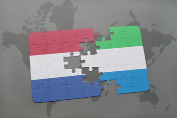 puzzle with the national flag of netherlands and sierra leone on a world map background.
