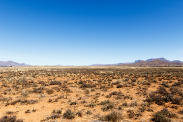 Fototapeta na wymiar Barren field with mountains and blue sky