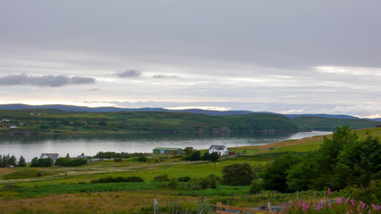 Fototapeta na wymiar lake with a solitary house and trees in the foreground in the Scottish highlands