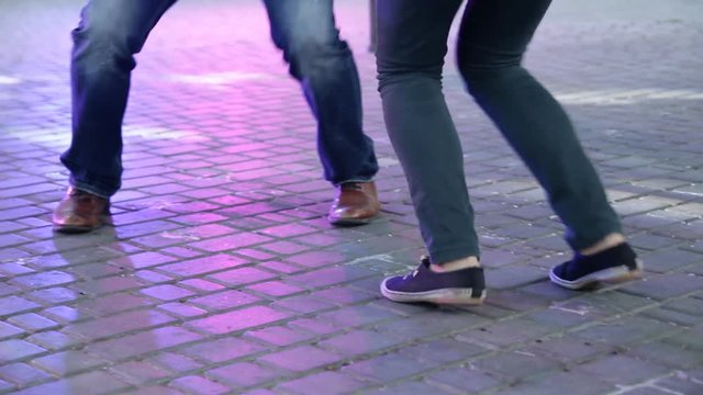 Dancer's legs perform lindy hop dance step on the city's square pavement. Street music day.