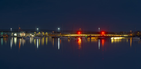 The moon and cityscape lights, reflect off harbour waters, poole