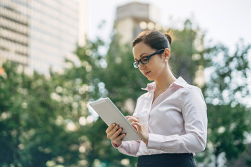Woman typing on touch screen of digital tablet, Businesswoman using modern tablet outside, Account manager working outdoor, blurred background