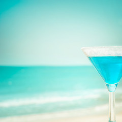Blue margarita cocktail at tropical ocean beach. Vintage style, hipster colors image with copy space for party invitation text