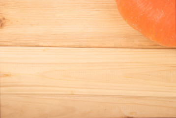 Closeup view of a part of orange pumpkin in the corner on wooden background with copyspace