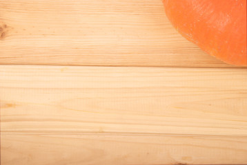 Closeup view of a part of orange pumpkin in the corner on wooden background with copyspace