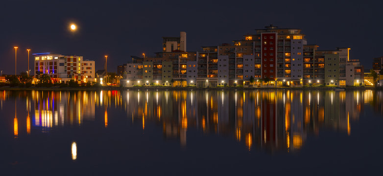 The moon and cityscape lights, reflect off harbour waters, poole