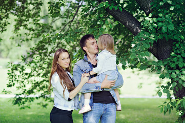 Family portrait in the nature - mother, father and daughter in denim.